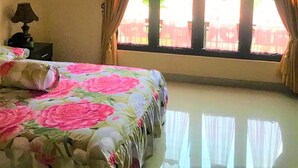 A bedroom with a bed, a nightstand, a lamp, and a window with curtains. - Poetri Guest House Syariah (Bogor)