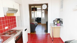 Une cuisine avec des carreaux rouges, un poêle et un évier. On y trouve également un coin repas avec un canapé et une table.