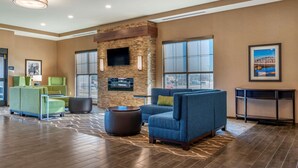 A spacious lobby with a stone fireplace, comfortable seating, large windows, and a flat-screen TV mounted on the wall. - Comfort Suites Camp Hill-Harrisburg West (Camp Hill)