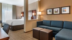 A hotel room with a bed, a sofa, a coffee table, a desk, and a chair. There are three framed pictures on the wall. - Comfort Suites Camp Hill-Harrisburg West (Camp Hill)