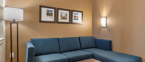 A blue sofa, a floor lamp, and three framed pictures on the wall.
