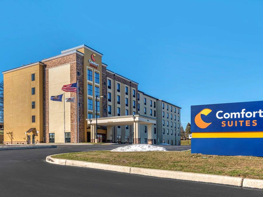 Ein Comfort Suites Hotel mit auffälliger Beschilderung, einer Flagge und einem gepflegten Eingangsbereich.