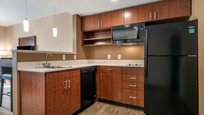 A modern kitchen with wooden cabinets, a black refrigerator, a microwave, and a dishwasher. - Comfort Suites Camp Hill-Harrisburg West (Camp Hill)