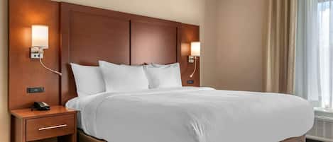 Una habitación de hotel con una cama grande, dos mesitas de noche, un teléfono y lámparas de pared.