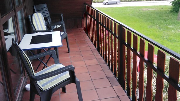 A covered outdoor area with a tiled floor, a table, and two chairs.