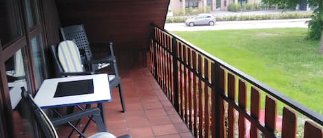 Un espace extérieur abrité, doté d’un sol carrelé, d’une table et de deux chaises.