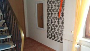 A staircase with blue carpeted steps leading to a door, a decorative metal partition, and a radiator with a yellow curtain.