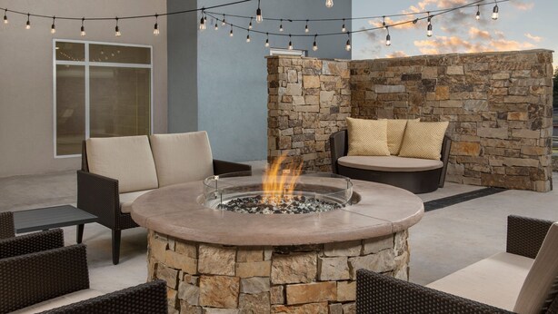 A stone fire pit surrounded by wicker furniture in an outdoor patio area. - Residence Inn by Marriott Lubbock-University Area (Lubbock)