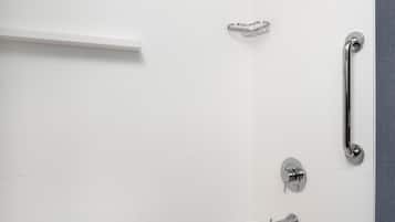 A modern bathroom with a white bathtub, a showerhead, a handrail, and a towel rack.