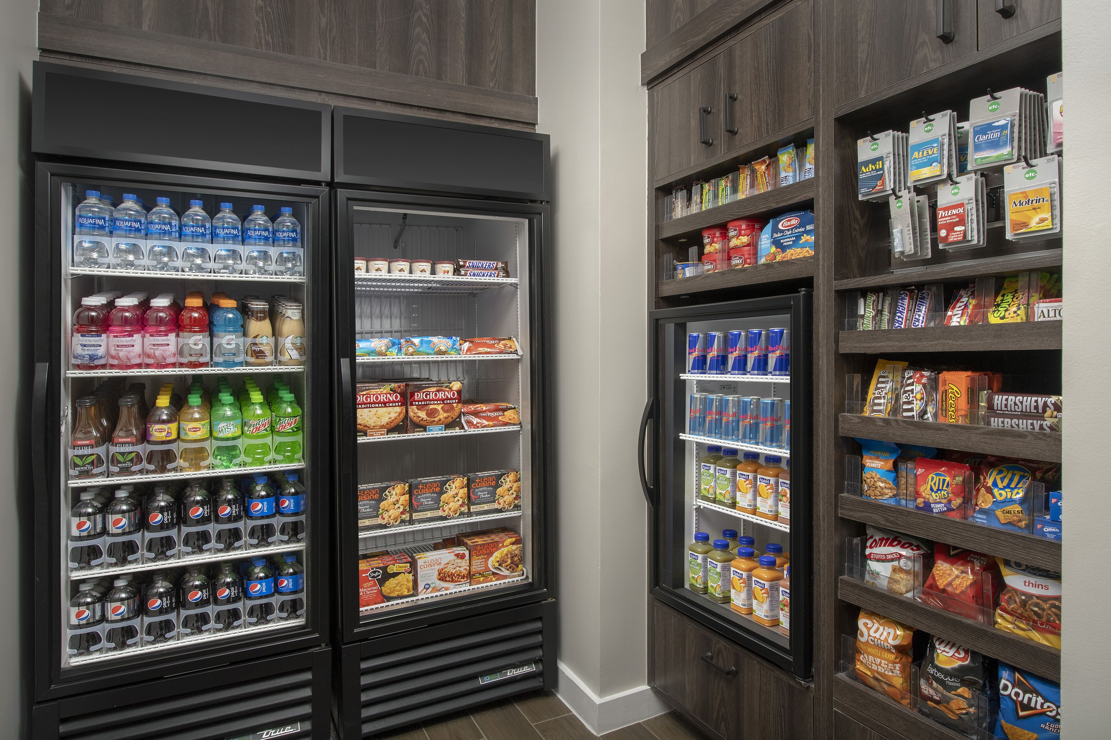 A refrigerated display case stocked with beverages and snacks, including water, soda, and various packaged foods.