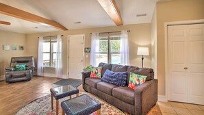 A spacious living room with a brown leather couch, two glass-top coffee tables, a dark brown armchair, and a floral rug. - Cozy Ironton Cabin w/ Shared Pool & Private Patio! (Ironton)