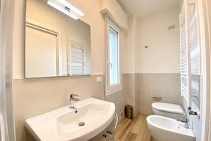 Une salle de bain équipée d’un lavabo, de toilettes et d’un bidet.