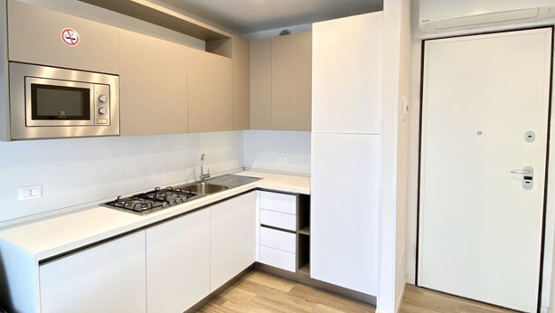 Una cocina moderna con gabinetes blancos, microondas integrado y estufa a gas.