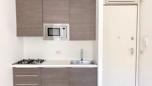 A compact kitchen with a built-in microwave, a gas stove, and a sink.