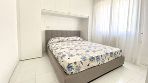 A bedroom with a bed, a wardrobe, and a window with curtains.