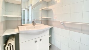 A modern bathroom with a white sink, mirror, and storage cabinets.