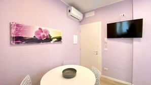 Une pièce dotée d’une table ronde, d’un téléviseur à écran plat fixé au mur et d’un appareil de climatisation.
