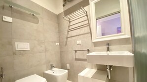 A modern bathroom with a bidet, a toilet, a sink, and a towel rack. - Appartamento Palladio 2 - Carraro Immobiliare Jesolo (Lido di Jesolo)