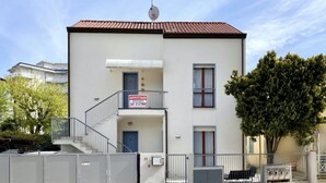 A two-story building with a satellite dish, a balcony, and a sign indicating apartments for rent.