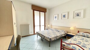 A bedroom with a bed, a desk, a chair, and a radiator.
