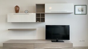 Ein modernes Wohnzimmer mit Flachbildfernseher, integrierten Regalen und minimalistischem Design.