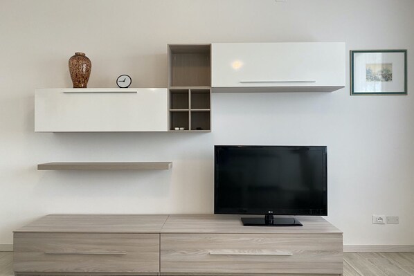 Un salon moderne doté d’un téléviseur à écran plat, d’étagères intégrées et d’un design minimaliste.