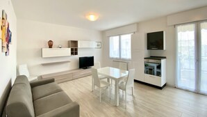 Eine moderne Wohnung mit Wohnbereich, Essplatz, Küchenzeile und einem Balkon.