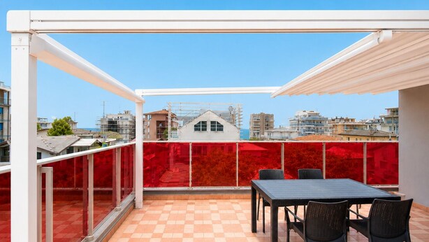 Un balcon doté d’un sol à carreaux, une table avec des chaises et une vue sur des bâtiments situés au loin.