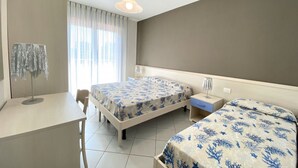 Una habitación de hotel con cama, escritorio, silla y ventana con cortinas.