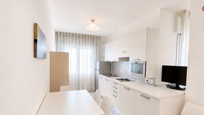 Una cocina moderna con armarios blancos, una mesa de comedor y un televisor.