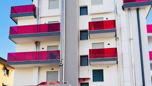 Un edificio de varios pisos con balcones, una ventana visible y cielo despejado.