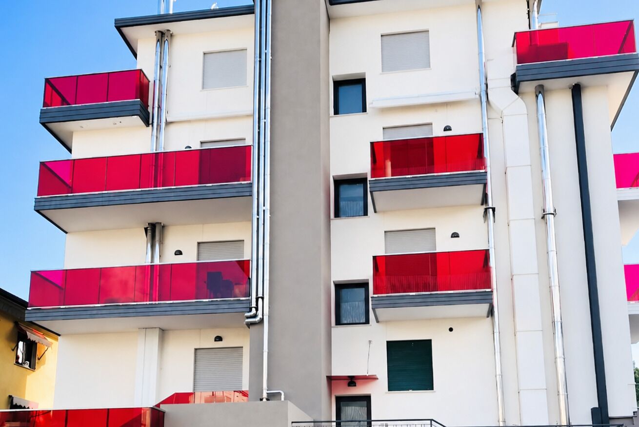 A multi-story building with balconies, a flat facade, and a clear sky.