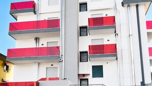A multi-story building with balconies, a flat facade, and a clear sky.