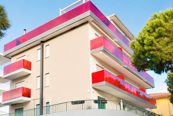 Un edificio de varios pisos con balcones, techo plano y cielo despejado.