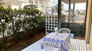 A patio with a table and chairs, surrounded by a wooden deck and a white fence. - Appartamento Tarvisium - Carraro Immobiliare Jesolo (Lido di Jesolo)