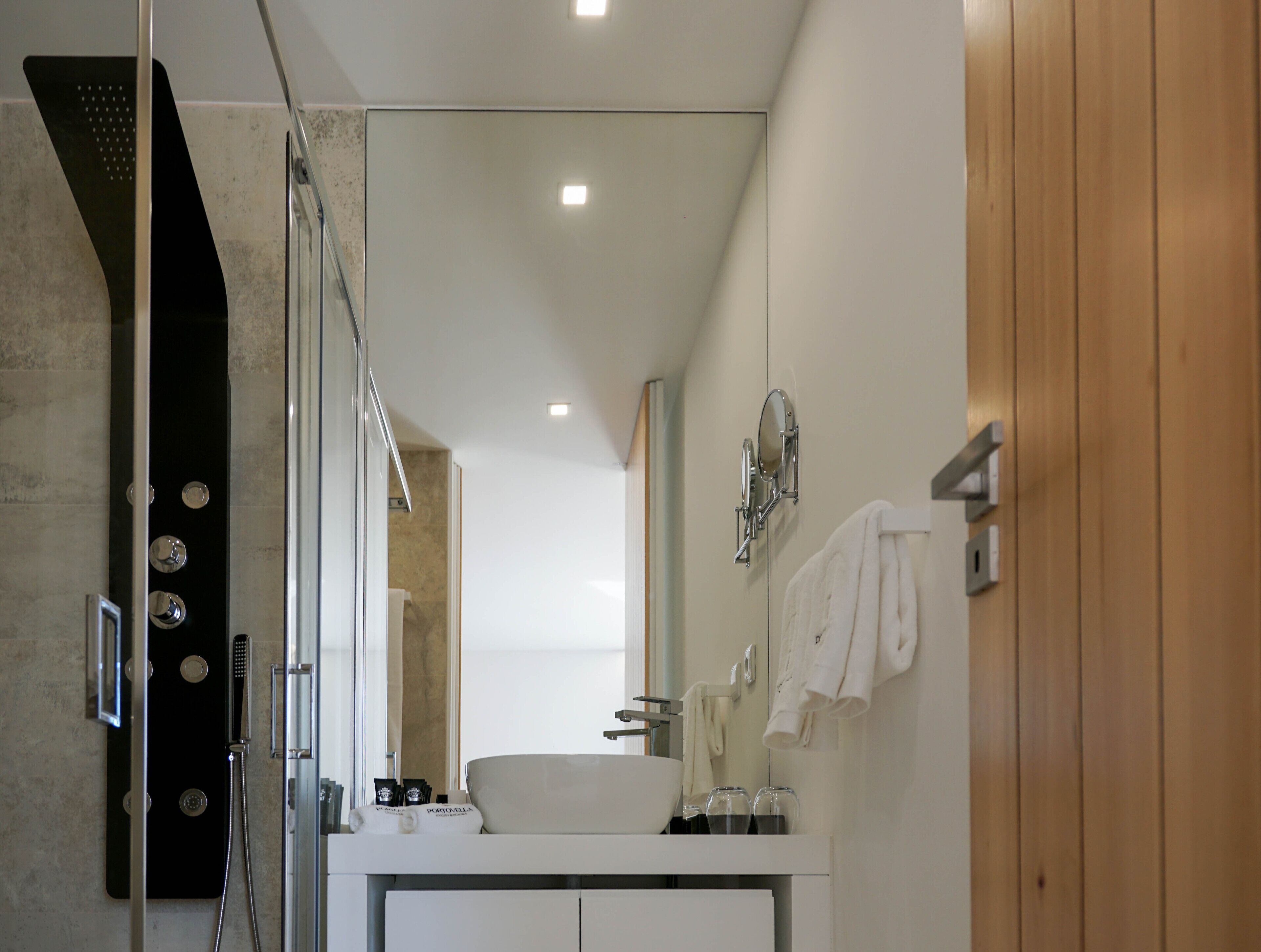 Un baño moderno con cabina de ducha de vidrio, un lavabo blanco y un espejo sobre él.