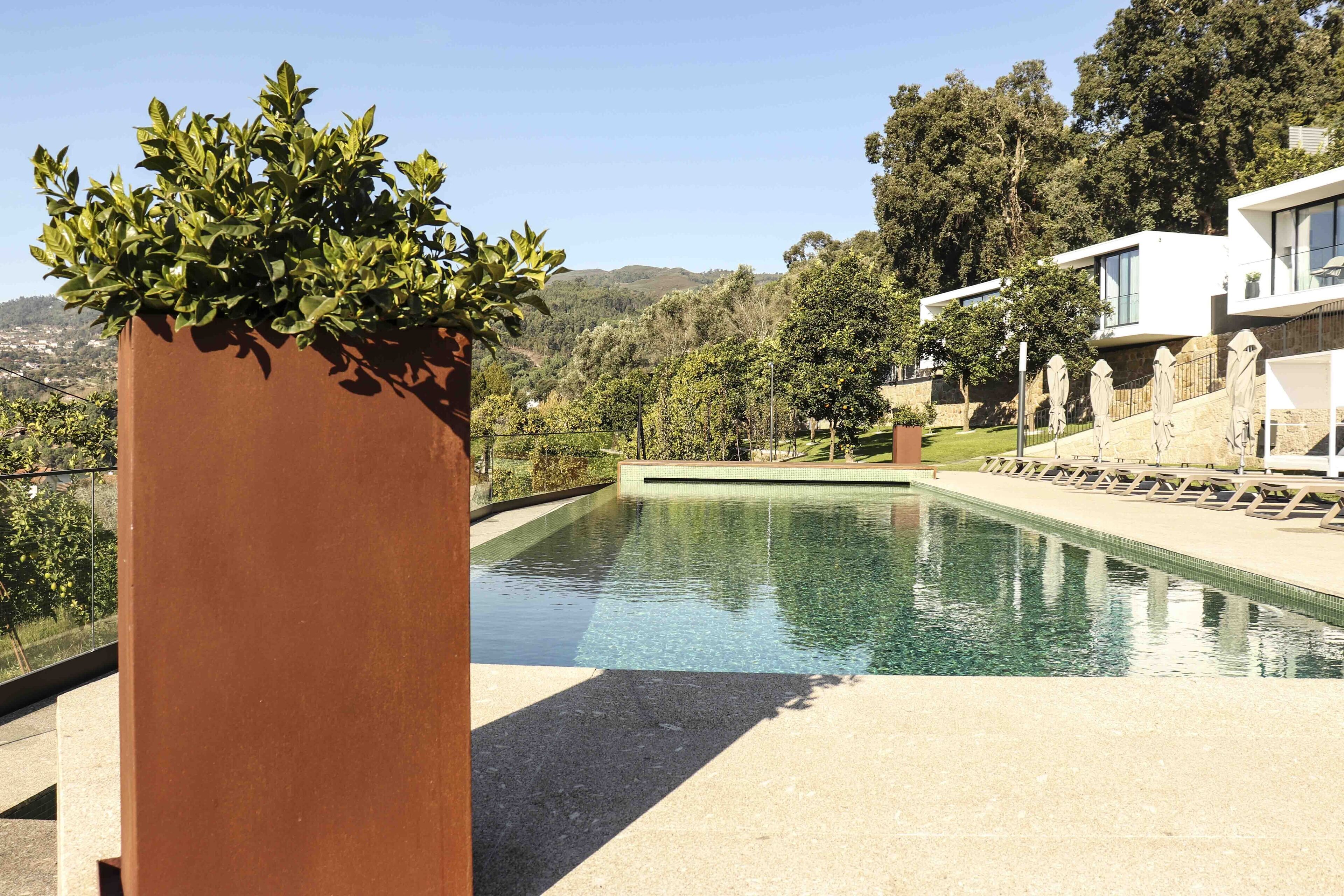 A modern pool area with a clear view of the surrounding landscape, including trees and hills.