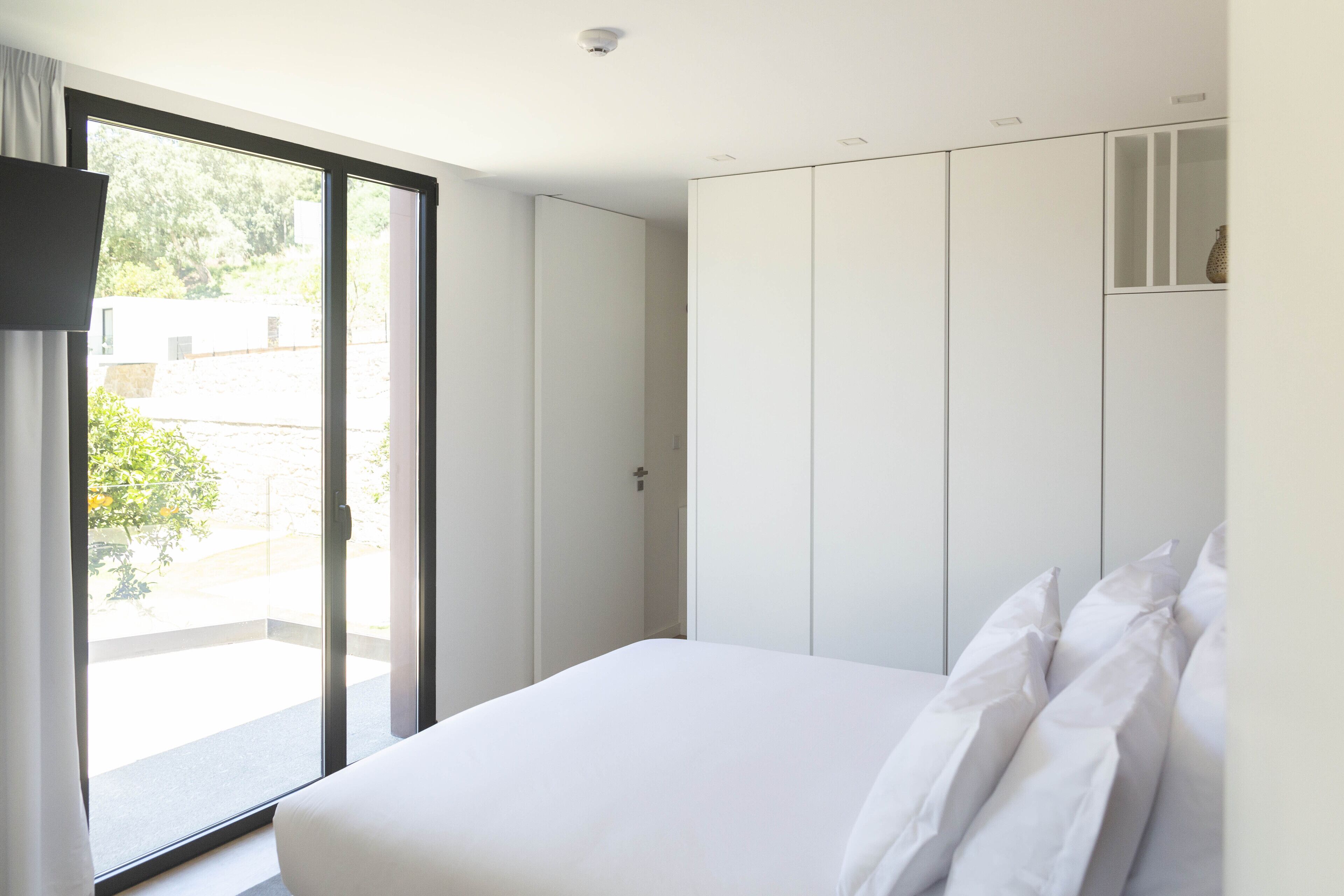 Un dormitorio con cama, puerta corredera a un balcón y armario.