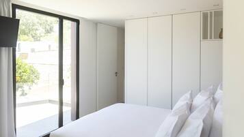 Un dormitorio con cama, puerta corredera a un balcón y armario.