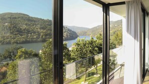 A modern room with large windows offering a scenic view of a lake and hills. - Portovella (Baiao)