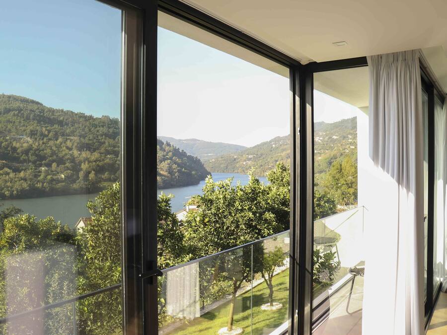 A modern room with large windows offering a scenic view of a lake and hills.