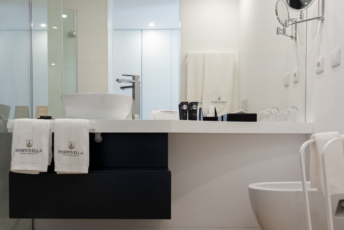Une salle de bain moderne avec un lavabo blanc, un miroir et un porte-serviettes avec des serviettes.