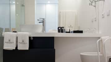 Een moderne badkamer met een witte wastafel, een spiegel en een handdoekrek met handdoeken.
