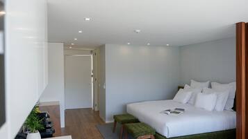 A modern hotel room with a large bed, a small seating area, and a bathroom visible through an open door.