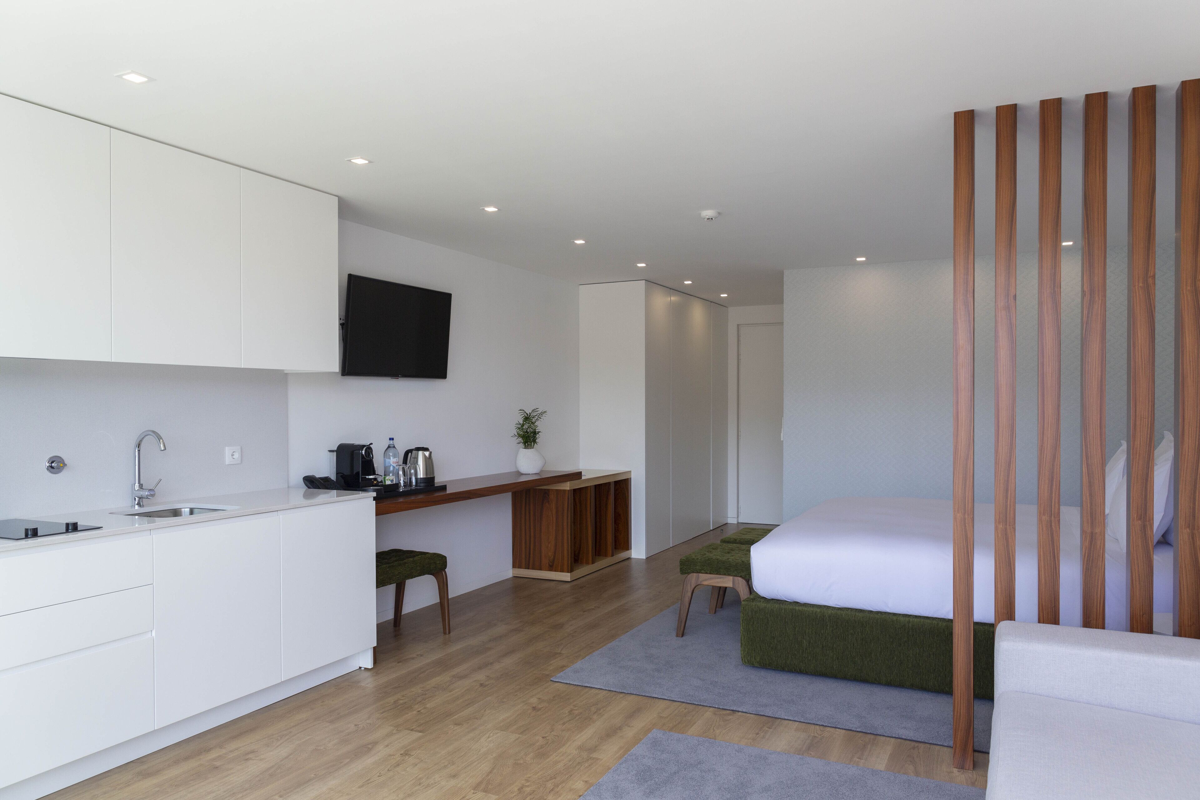 Ein modernes, kleines Zimmer mit Küchenzeile, einem Bett und einer Holzwand.