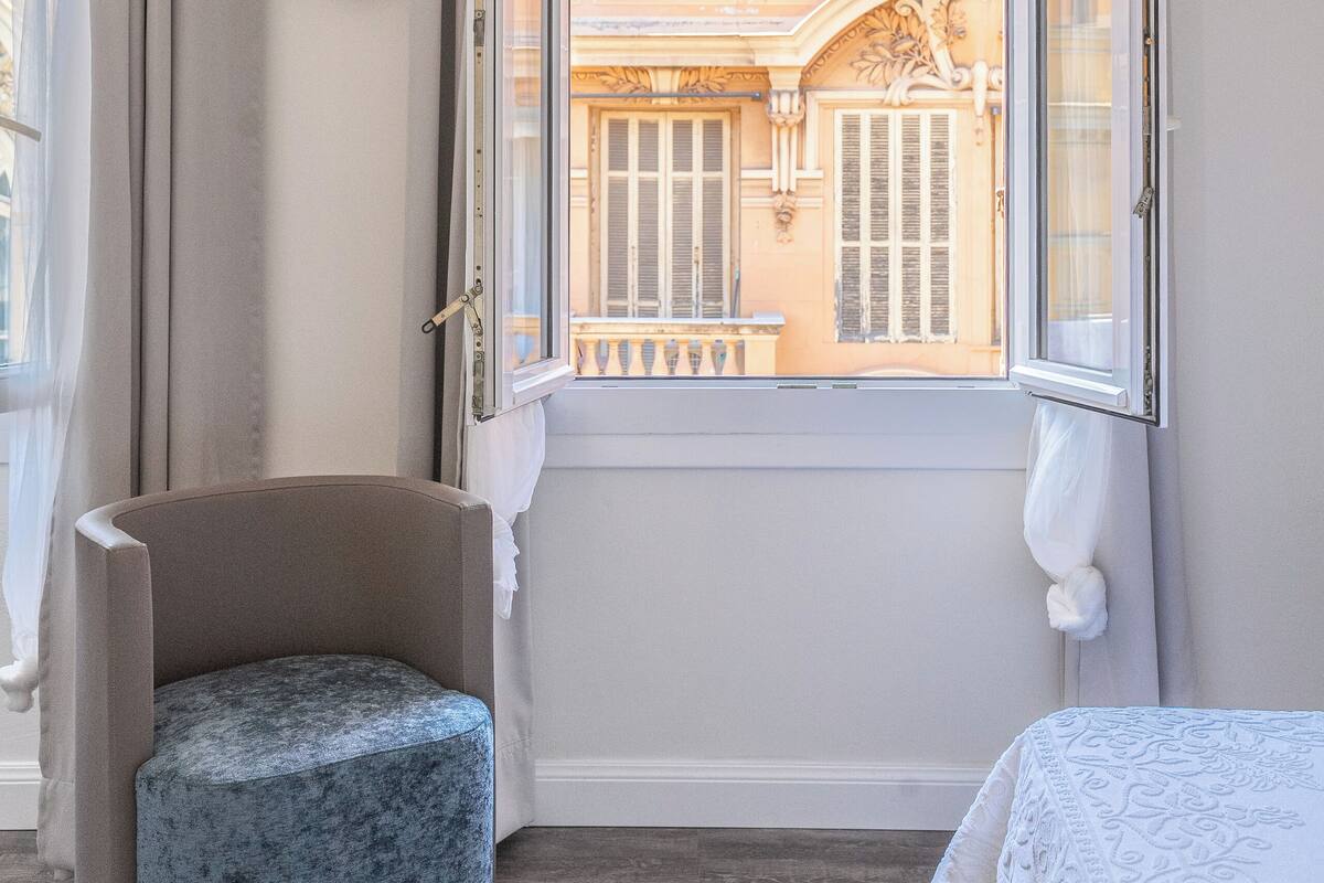 A room with a large window, a chair, and a bed.