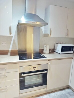 A modern kitchen with a stainless steel range hood, a built-in oven, a microwave, and a coffee maker.
