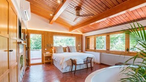 Une chambre avec un grand lit, un coin salon et une baignoire.
