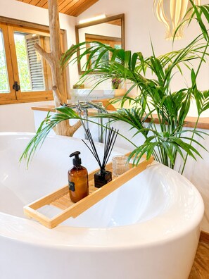 Ein modernes Badezimmer mit einer großen Badewanne, Holzakzenten und üppigen Grünpflanzen.