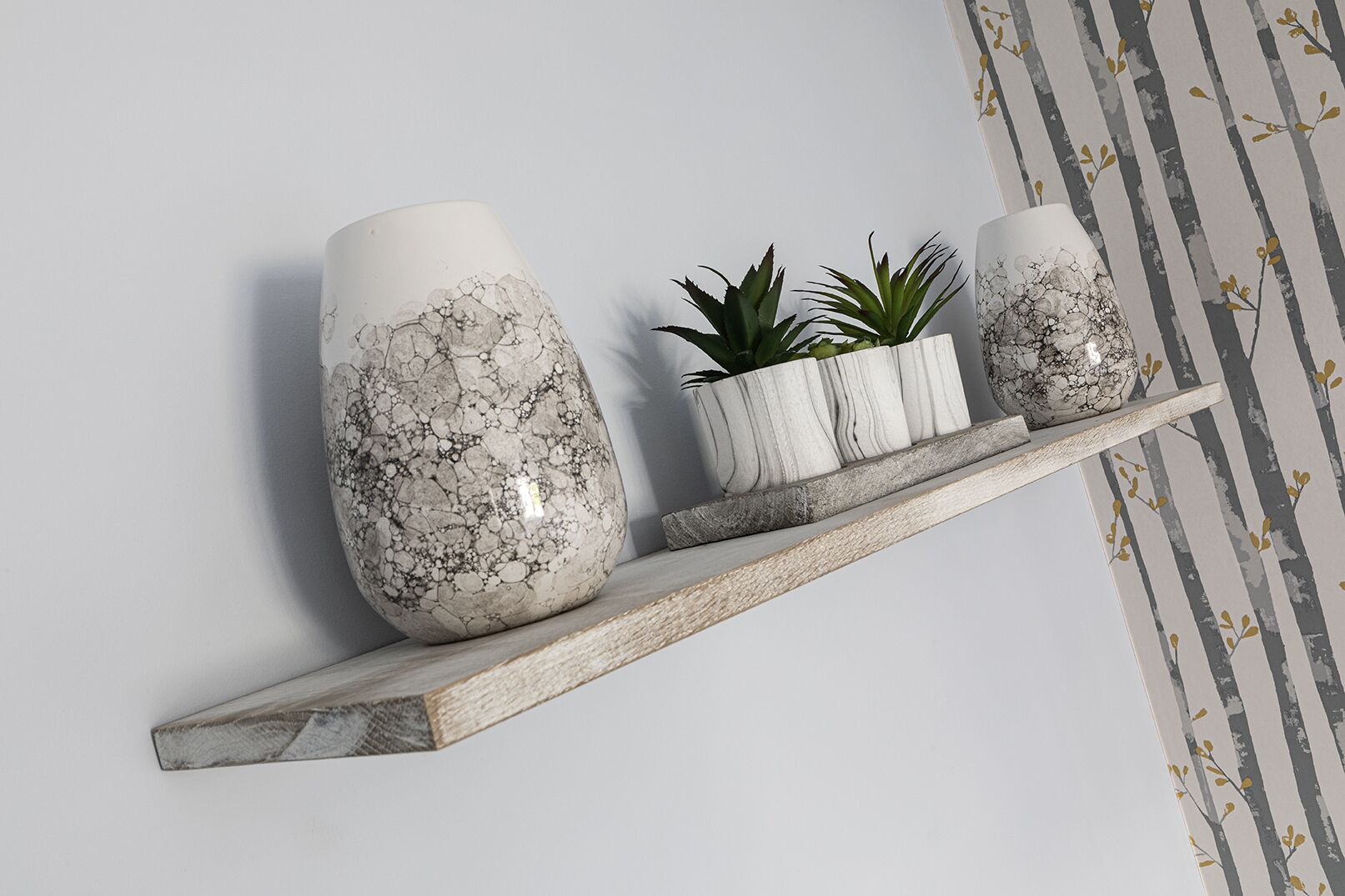 A shelf with three decorative vases and a small plant.